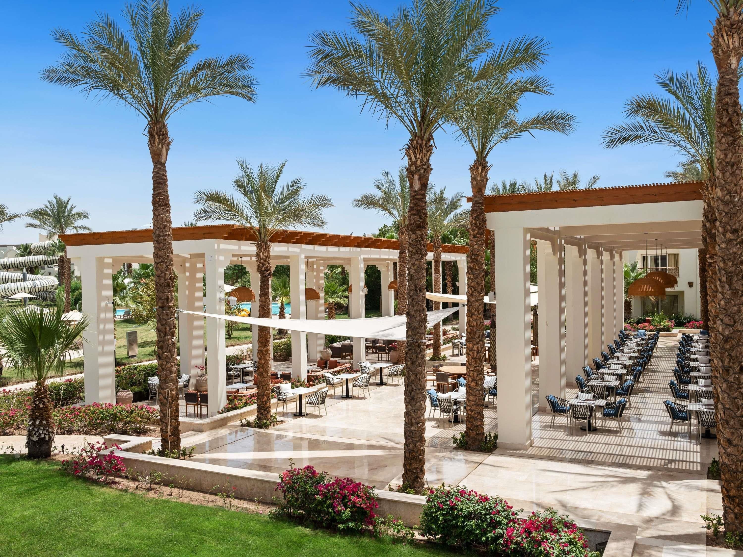 A resort with outdoor seating, palm trees, and a pool.