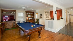 Un salon spacieux équipé d’une table de billard, d’un téléviseur et d’une bibliothèque.