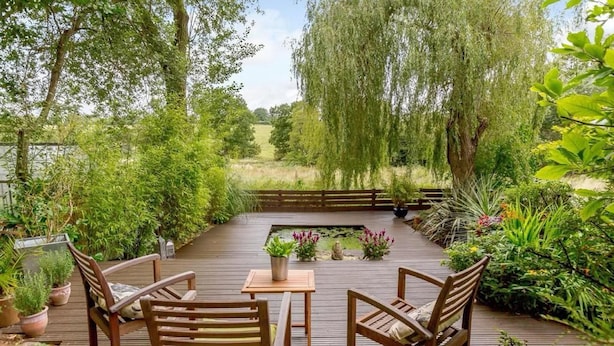 Une terrasse extérieure avec des meubles en bois et un bassin.