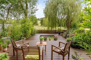 Una terraza al aire libre con mobiliario de madera y un estanque.