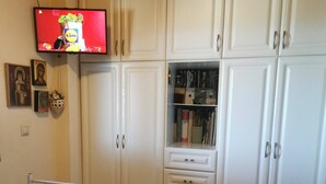 Een slaapkamer met een bed, twee handdoeken met bloemen, een televisie en een kledingkast.
