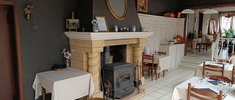 Une salle à manger traditionnelle avec une cheminée, des tables et des chaises en bois.