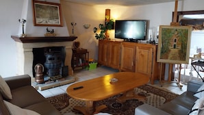 Una sala de estar con chimenea, televisor, un cuadro y un sofá.