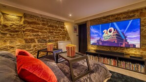 Een gezellige woonkamer met een stenen muur, een flatscreen televisie, popcorn en een boekenkast.