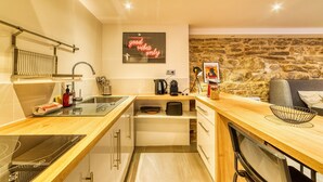 Een kleine keuken met een stenen muur, een houten aanrecht en een neonreclame.