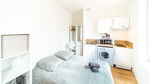 Habitació petita amb llit, rentadora i bugateria.