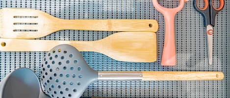 Een vloermat in de keuken met verschillende keukengerei, zoals een mes, spatels, tangen en een opscheplepel.