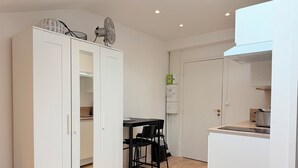 Une cuisine compacte avec un coin repas, des meubles blancs et un petit plan de travail.