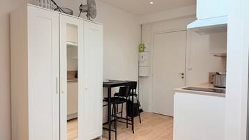 Une cuisine compacte avec un coin repas, des meubles blancs et un petit plan de travail.
