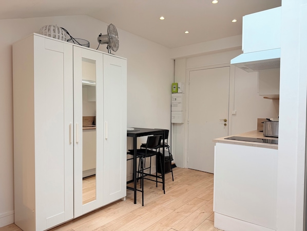 Une cuisine compacte avec un coin repas, des meubles blancs et un petit plan de travail.