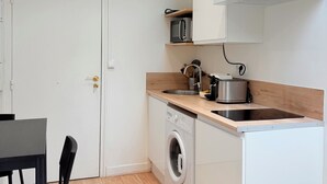 Une cuisine compacte équipée d’un lave-linge, d’un four à micro-ondes et d’un grille-pain posés sur le plan de travail.