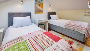 A bedroom with two beds, a small desk, and a hanging light fixture. - Host & Stay | Millers Coach House (Hexham)