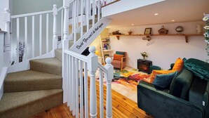 A staircase leading to a loft bedroom with a bed, a green sofa, and a bookshelf. - Host & Stay | Millers Coach House (Hexham)