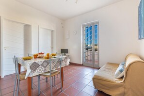 A dining area with a table set for four, a sofa, and a door leading outside. - 3684 TSG - Casa Facci te Rosa by Barbarhouse (Ugento)
