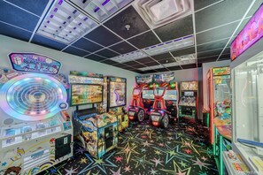 An arcade with various gaming machines, a prize display, and a star-patterned floor.