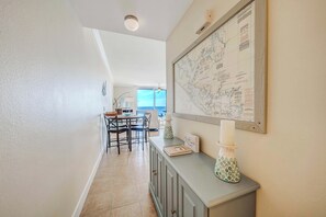 A hallway with a dining area, a map on the wall, and a cabinet with decorative items.