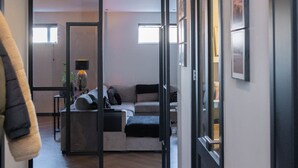 A hallway leading to a living area with a sofa and a lamp.
