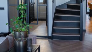 A modern interior with a staircase, a dining area with a table and chairs, and a potted plant.