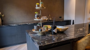 A kitchen with a marble countertop, a tiered serving tray, and various kitchen items.