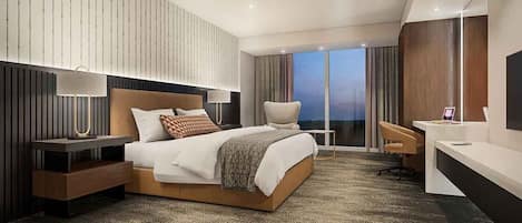 Ein modernes Hotelzimmer mit einem großen Bett, einem Schreibtisch und Blick auf die Stadt.