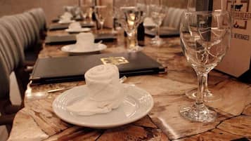 Una mesa de comedor dispuesta con platos, una servilleta doblada, una copa de vino y un menú.