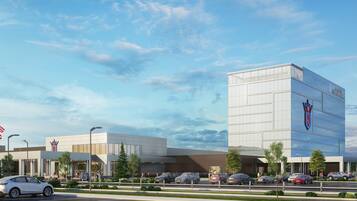 A modern building with a prominent logo on the facade, surrounded by a parking lot with several cars.