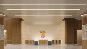 A modern reception area with a central emblem, linear ceiling lights, and a patterned floor.