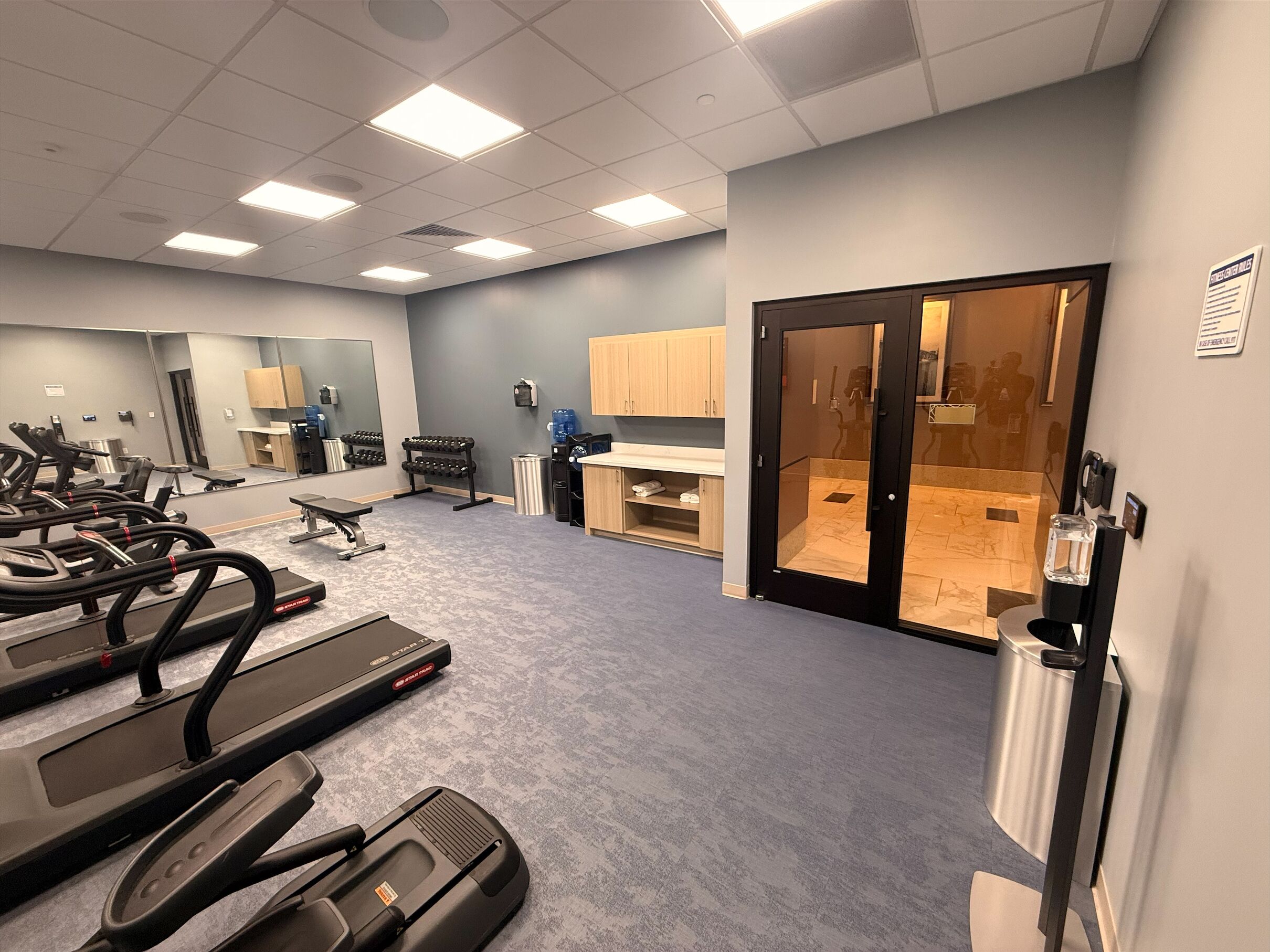 A gym with treadmills, weights, and a water dispenser.