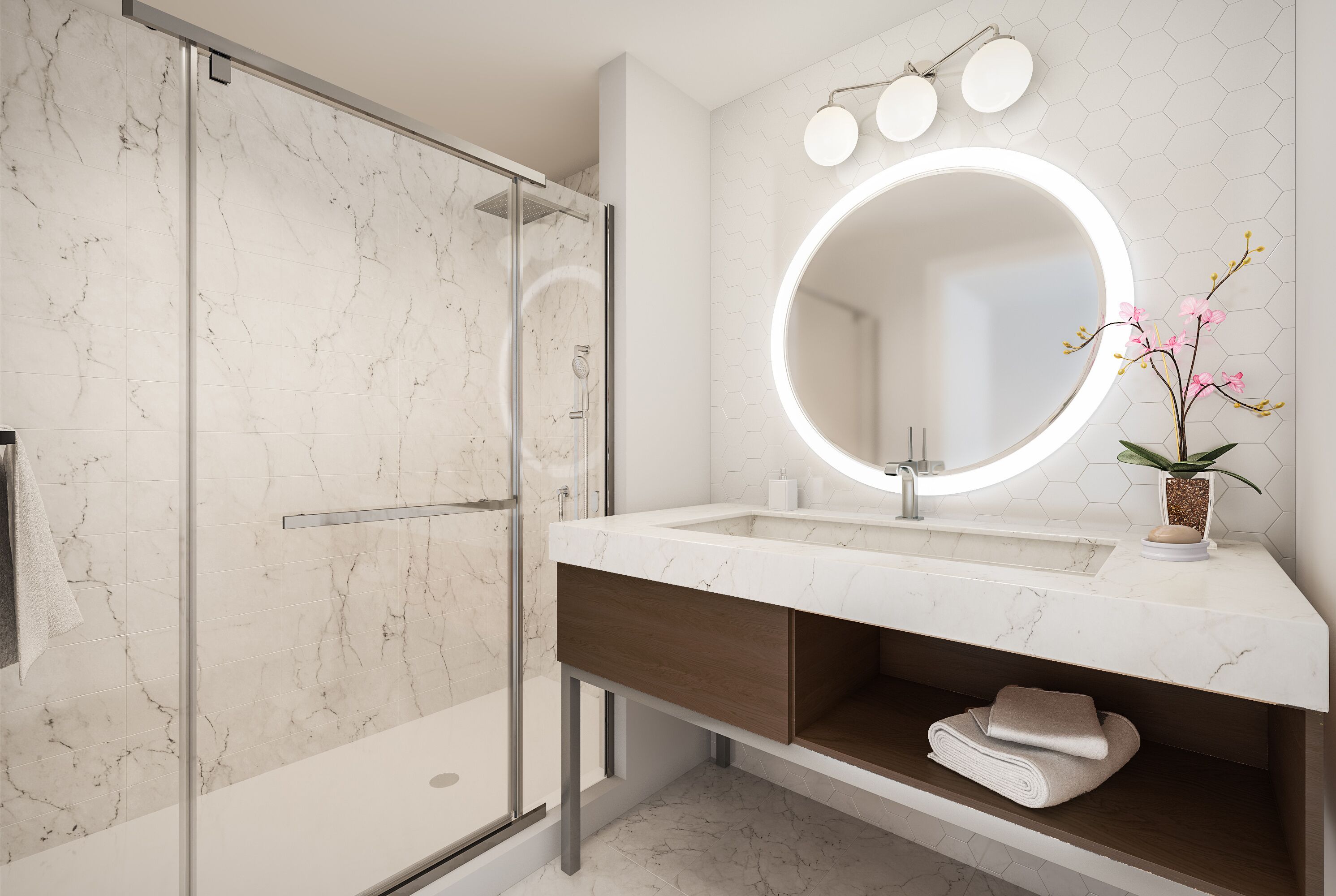 A modern bathroom with a glass-enclosed shower, a marble-tiled wall, a white sink with a wooden vanity, and a round mirror with lights.