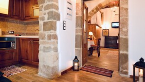 A kitchen with wooden cabinets, a stone pillar, and a microwave.