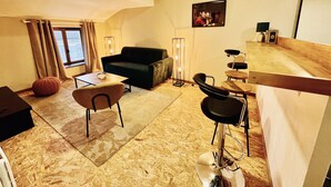 Un salon moderne comprenant un canapé, une table basse, une table à manger avec des chaises et un coin bar.