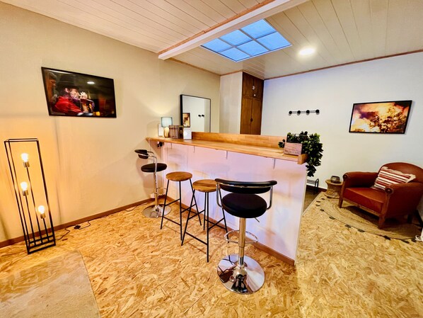 A modern kitchen with a bar area, wooden flooring, and a skylight.