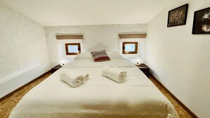 Une chambre à coucher avec un grand lit, deux fenêtres et une table de chevet avec une lampe.