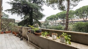 A rooftop terrace with potted plants and a view of surrounding buildings.