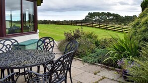 A patio with a table and chairs, a wooden fence, and a grassy field in the background. - 2 Bedroom bungalow Aberdeen within the beautiful countryside. (Aberdeen)