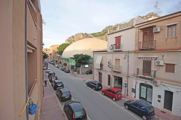 A street view with parked cars, buildings, and a large dome structure in the background.