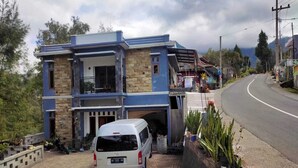 A two-story building with a garage, parked van, and potted plants. - Villa Ricky Gunung Bromo  (Ngadisari)