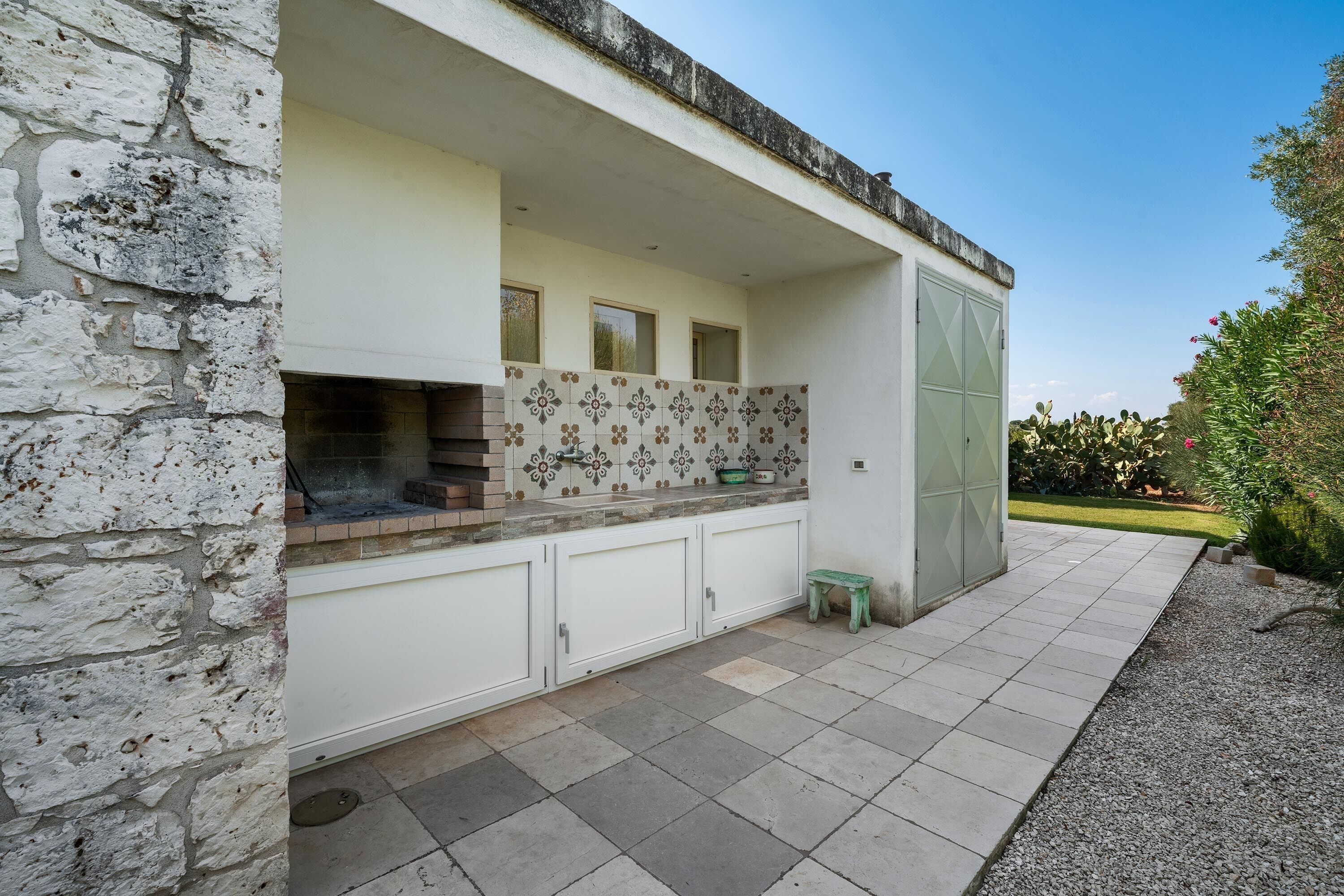 Una cocina con pared de piedra, salpicadero de azulejos y un taburete pequeño.