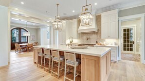 A spacious kitchen with a large island, wooden bar stools, and pendant lighting. - Ultra Luxe Home, Pool & Spa, Screened Porch, 5 Min Walk to Beach (Hilton Head Island)