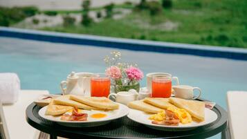 A breakfast setup with toast, eggs, and bacon on a table by a pool.