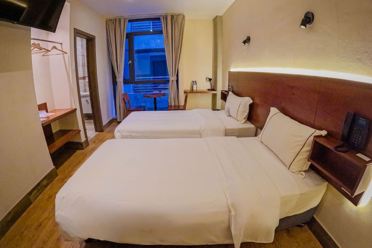 Une chambre d’hôtel avec deux lits, un bureau, une chaise et une petite table.