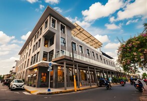 Un edificio moderno con techo plano, amplios ventanales y un área de entrada cubierta.