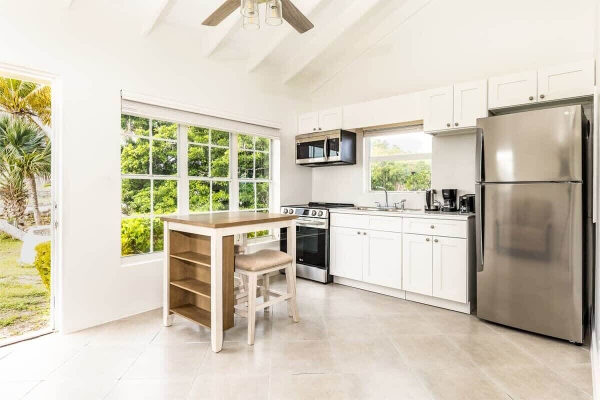 A modern kitchen with white cabinets, a stainless steel refrigerator, a microwave, and a stove.