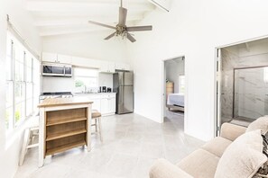 Una cocina amplia con armarios blancos, un refrigerador de acero inoxidable y una mesa de comedor de madera.