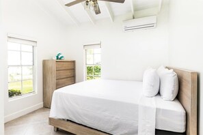 Un dormitorio con cama, cabecero de madera y dos ventanas.