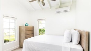 Une chambre à coucher avec un lit, une tête de lit en bois et deux fenêtres.