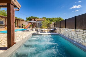 Ein Swimmingpool mit LiegestĂŒhlen, einer Rutsche und einer Steinmauer.