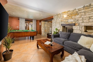 A living room with a pool table, a sofa, a coffee table, and a stone wall.