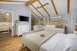 Ein Schlafzimmer mit einem Bett, einem Schminktisch, einem Fernseher und einer Steinwand.