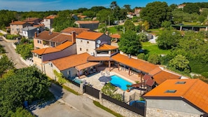 Ein Wohngebiet mit SteinhĂ€usern, einem Schwimmbad und einer grĂŒnen Landschaft.